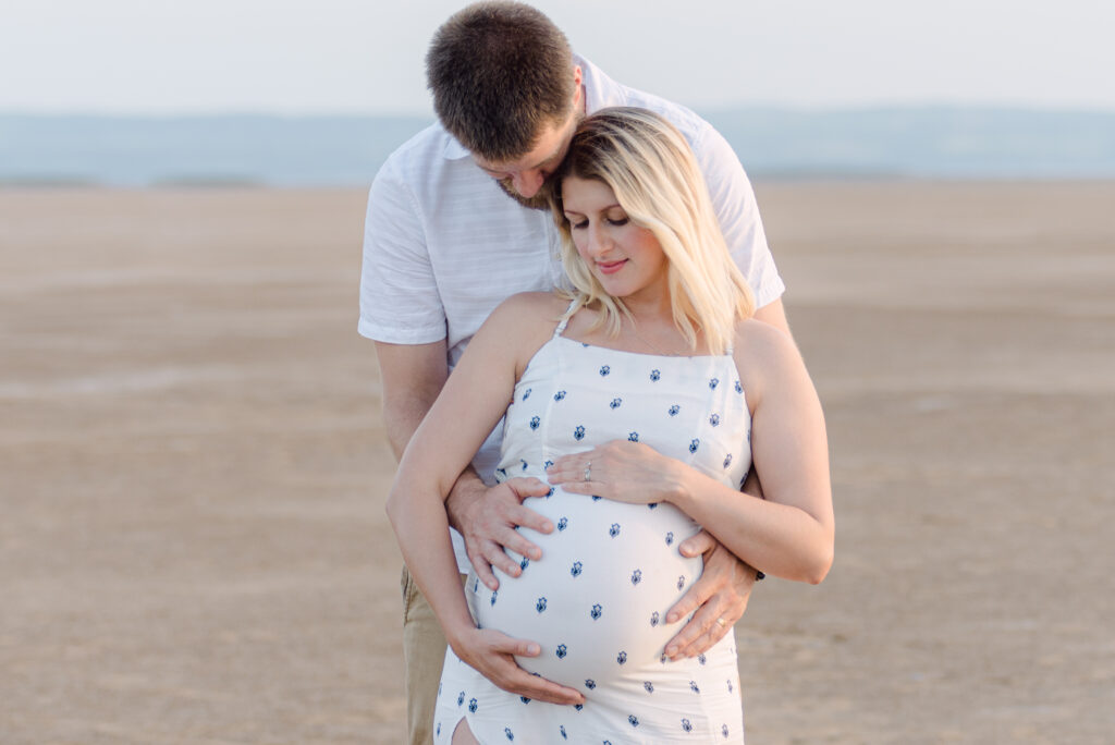 Beautiful couple at sunset, cradling pregnancy bump by maternity photographer wirral